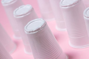 Pembe arka planda plastik gözlük. Tek kullanımlık sofra takımı. Plastik ürünler.