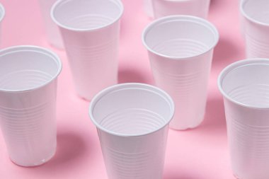Pembe arka planda plastik gözlük. Tek kullanımlık sofra takımı. Plastik ürünler.