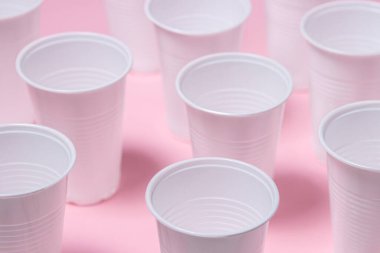 Pembe arka planda plastik gözlük. Tek kullanımlık sofra takımı. Plastik ürünler.