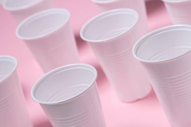 Pembe arka planda plastik gözlük. Tek kullanımlık sofra takımı. Plastik ürünler.