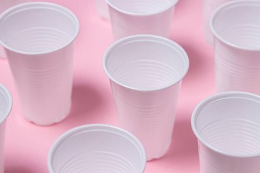 Pembe arka planda plastik gözlük. Tek kullanımlık sofra takımı. Plastik ürünler.