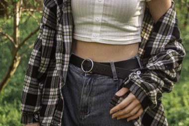 Doğanın arka planındaki kadın figürü. İnce, zarif bel. Kadın modası, kemerli kot pantolon.