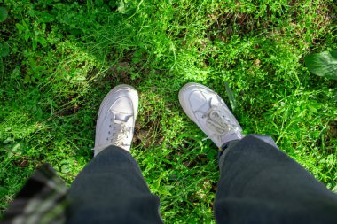 Bacakları yeşil çimlerin üzerinde spor ayakkabılarıyla. Yeşil çimlerin üzerinde yürüyorum.