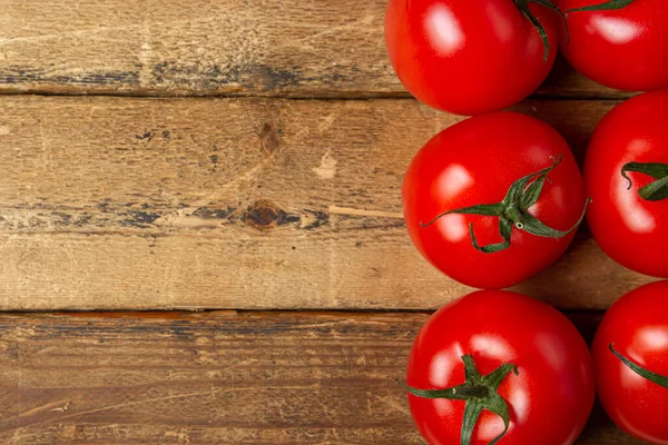 stock image Tomatoes on a wooden background. Ripe and fresh tomatoes. Healthy vegetables. There is a place for an inscription or logo