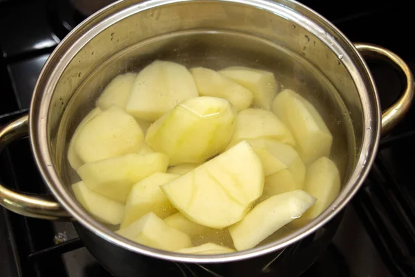 Patatesleri tencerede kaynatın. Suda patates soymak. Ev yemeği.