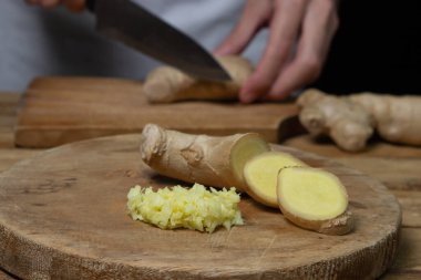 Ahşap arka planda zencefil. Şef zencefil kökünü keser. Zencefil pişiriyorum. Sağlıklı yemek.