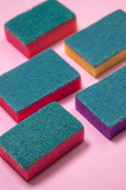 Pembe arka planda sünger yıkıyorum. Renkli bir arka planda temizlik süngeri. Ev yıkama ve temizlik aletleri.