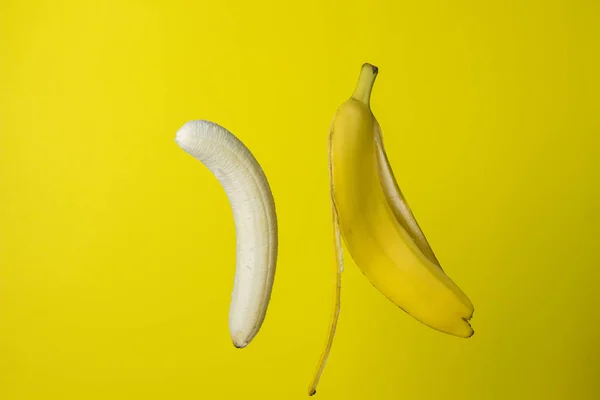 黄色背景的香蕉 亮晶晶的水果彩色背景的皮旁边有剥皮的香蕉 — 图库照片