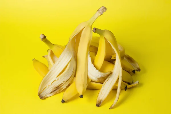 香蕉在黄色的背景上剥皮 彩色背景上的生物碎片 — 图库照片
