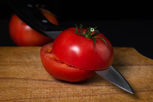 토토는 도마를 반으로 잘랐다 어두운 배경에 토마토와 있습니다 — 스톡 사진
