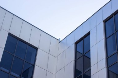 Gökyüzüne karşı modern ofis binası. Bir iş binasının cephesi. Ofis pencereleri.