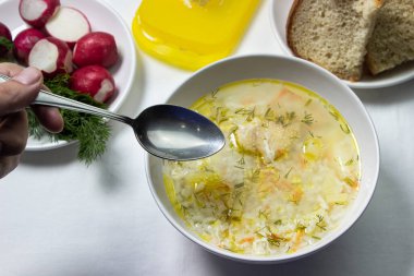 Beyaz masa örtüsü üzerinde ev yapımı pirinç çorbası. Besleyici bir öğle yemeği. Sağlıklı beslenme kavramı