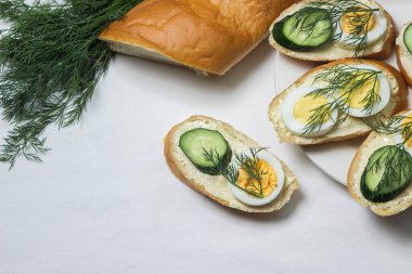 Beyaz masa örtüsü üzerinde sandviçler. Bir şeyler atıştır. Kahvaltı için lezzetli ve hafif sandviçler.