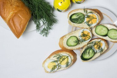 Beyaz masa örtüsü üzerinde sandviçler. Bir şeyler atıştır. Kahvaltı için lezzetli ve hafif sandviçler.