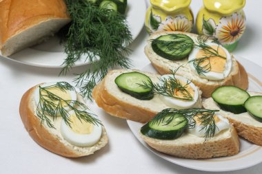 Beyaz masa örtüsü üzerinde sandviçler. Bir şeyler atıştır. Kahvaltı için lezzetli ve hafif sandviçler.