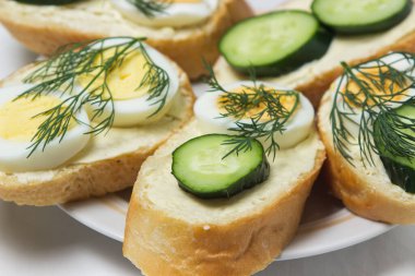 Beyaz masa örtüsü üzerinde sandviçler. Bir şeyler atıştır. Kahvaltı için lezzetli ve hafif sandviçler.