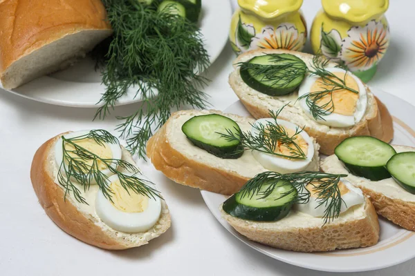 Beyaz masa örtüsü üzerinde sandviçler. Bir şeyler atıştır. Kahvaltı için lezzetli ve hafif sandviçler.