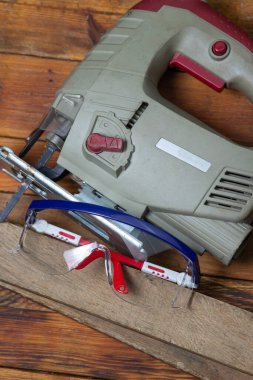 Tahta bir arka planda yapboz ve güvenlik gözlükleri. Elektrikli ahşap işçiliği aracı