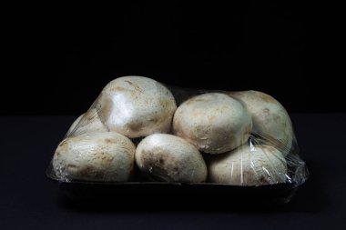 Şampiyonlar siyah arka planda bir konteynırda toplanmış. Paketlemede taze mantarlar