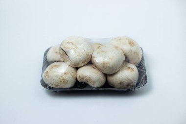 Şampiyonlar beyaz arka planda bir konteynırda toplanmış. Paketlemede taze mantarlar