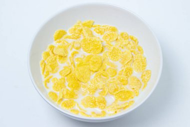 Beyaz arka planda sütlü mısır gevreği. Sağlıklı ve lezzetli bir kahvaltı..