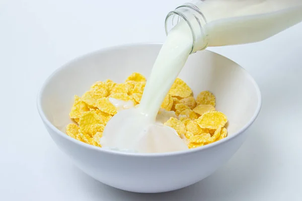 Melk Wordt Gegoten Een Bord Met Cornflakes Een Witte Achtergrond — Stockfoto