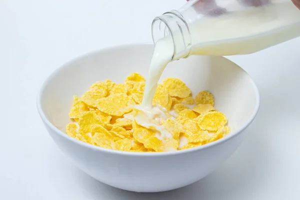 Latte Viene Versato Piatto Con Cornflakes Fondo Bianco Colazione Sana — Foto Stock