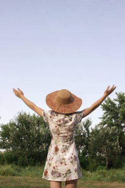 Kız, doğanın arka planına fotokopi çekerek ellerini kaldırıyor. Hayatın ve doğanın tadını çıkar.