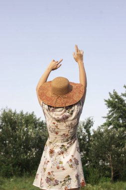 Kız, doğanın arka planına fotokopi çekerek ellerini kaldırıyor. Hayatın ve doğanın tadını çıkar.