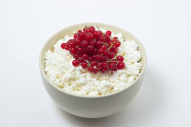 Beyaz tabakta kırmızı üzümlü süzme peynir. Lezzetli ve sağlıklı bir kahvaltı. Uygun beslenme