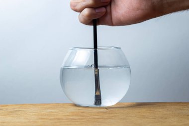 Bir boya fırçası beyaz arka planda bir kavanoz suya batırılır. Çizim için elele tutuşan kemik