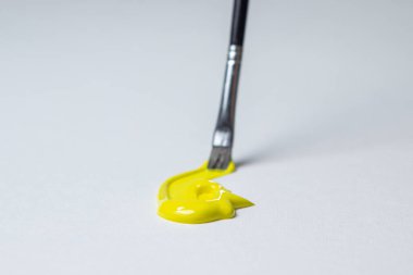 Beyaz arka planda sarı boyayla boyamak için fırça. Suluboya boya