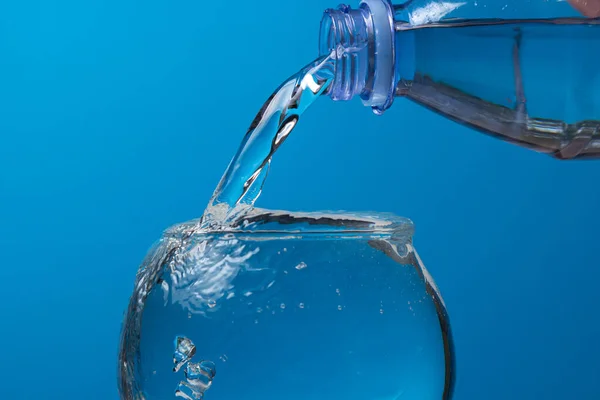 Água Derramada Copo Uma Garrafa Plástico Fundo Azul Água Potável — Fotografia de Stock