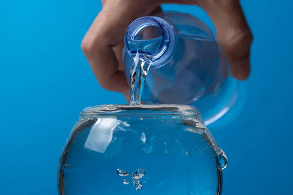 Água Derramada Copo Uma Garrafa Plástico Fundo Azul Água Potável — Fotografia de Stock