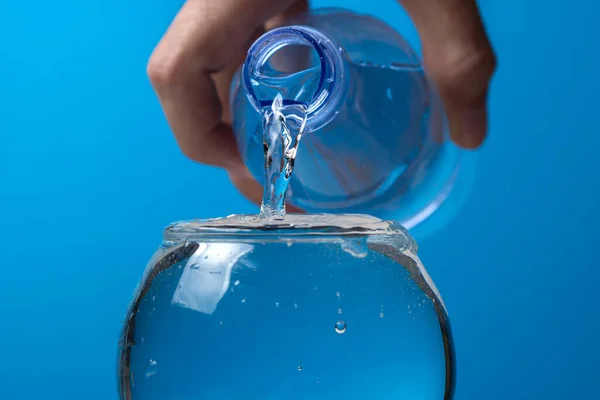 Água Derramada Copo Uma Garrafa Plástico Fundo Azul Água Potável — Fotografia de Stock