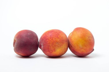 Beyaz arka planda şeftaliler. Arka arkaya üç olgun şeftali. Sağlıklı beslenme.