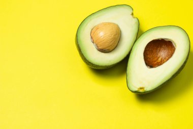 Sarı arka planda avokado. Renkli arkaplanda avokadoyu kes