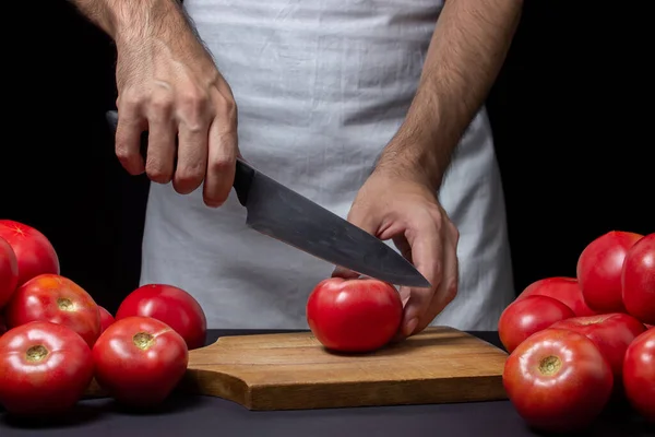 토마토는 바탕에 요리사가 어두운 배경에서 토마토를 자르는 — 스톡 사진