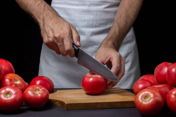 토마토는 바탕에 요리사가 어두운 배경에서 토마토를 자르는 — 스톡 사진