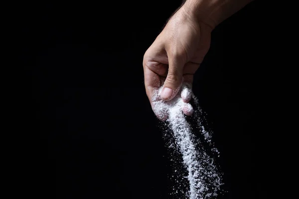 Siyah arka planda tuz. El, arka plana tuz serper.