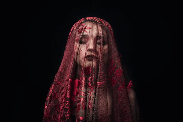 Kızın yüzü siyah bir arka planda kırmızı bir peçe ile kaplıdır. Koyu renk bir kız resmi