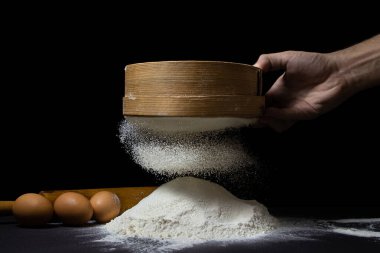 Un, siyah bir arka planda elekten geçirilir. Koyu arkaplanda en yüksek kalitede un.