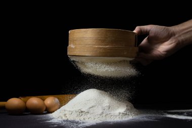 Un, siyah bir arka planda elekten geçirilir. Koyu arkaplanda en yüksek kalitede un.