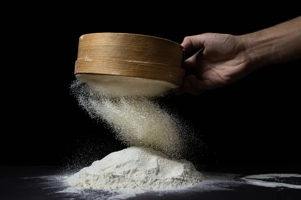 Un, siyah bir arka planda elekten geçirilir. Koyu arkaplanda en yüksek kalitede un.