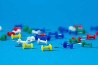 Mavi arka planda çok renkli raptiyeler. Ofis sayfası.