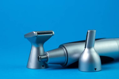 Mavi arka planda erkek elektrikli tımar seti. Eklentileri olan erkek budayıcısı