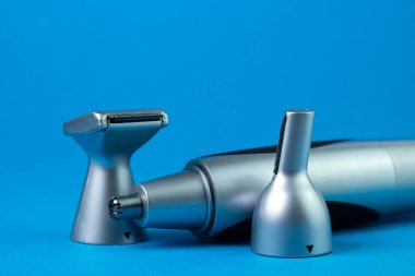 Mavi arka planda erkek elektrikli tımar seti. Eklentileri olan erkek budayıcısı