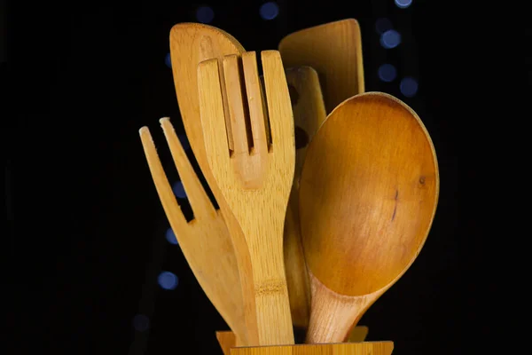 Mutfak ahşap çatal bıçakları siyah arka planda ışıklarla.