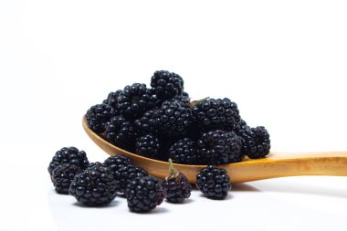 Beyaz arka planda böğürtlenli tahta kaşık. Lezzetli olgun çilek.