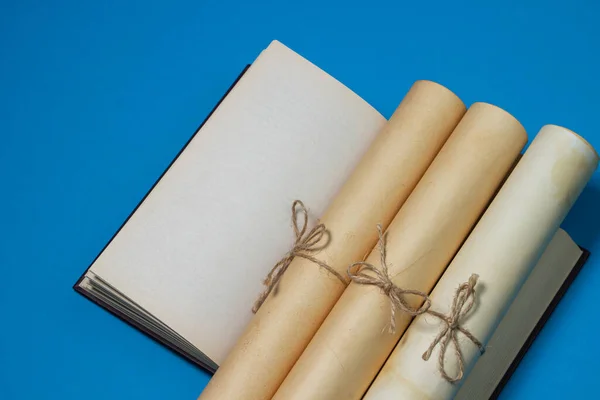 Old scrolls and books on a blue background. Knowledge and education concept. Blank book page on copy space